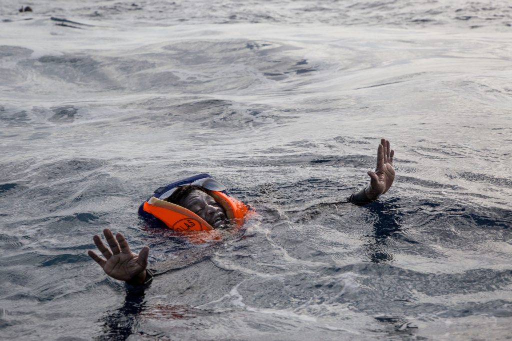 TOPSHOT - A migrant tries to board a boat of the German NGO Sea-Watch in the Mediterranean Sea on November 6, 2017. During a shipwreck, five people died, including a newborn child. According to the German NGO Sea-Watch, which has saved 58 migrants, the violent behavior of the Libyan coast guard caused the death of five persons. / AFP PHOTO / Alessio Paduano (Photo credit should read ALESSIO PADUANO/AFP/Getty Images)