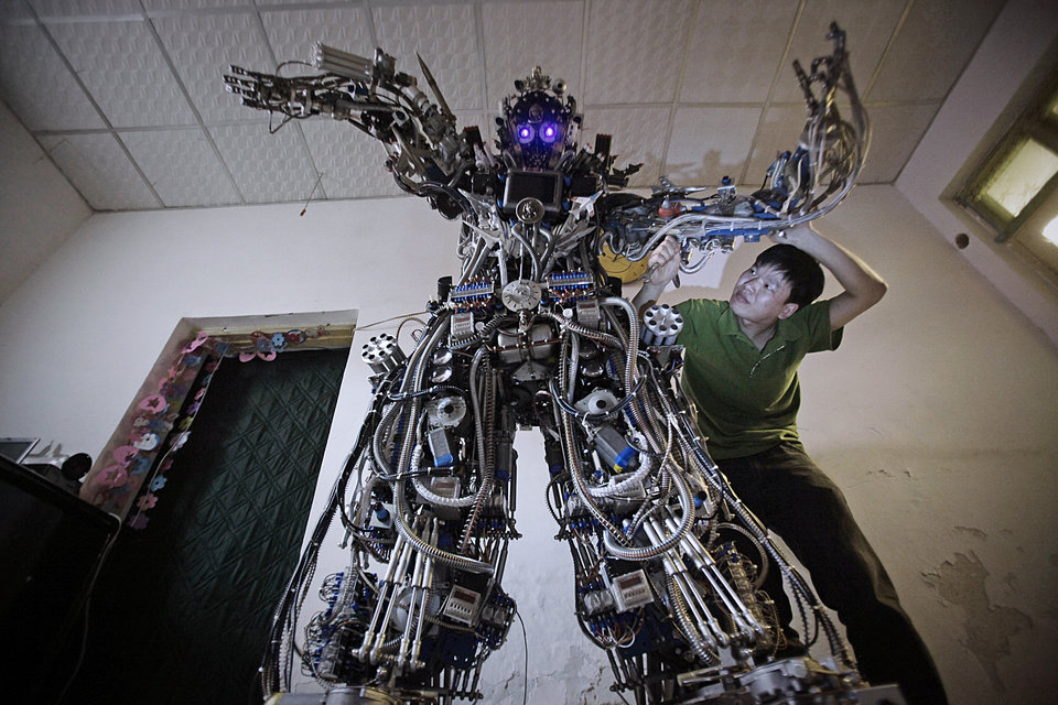 Chinese inventor Tao Xiangli modifies the circuits of his self-made robot at his house in Beijing, May 15, 2013. Tao, 37, spent about 150,000 yuan (USD 24,407 ) and more than 11 months to build the robot out of recycled scrap metals and electric wires that he bought from a second-hand market. The robot is 2.1-metre-tall and around 480 kilograms (529 lbs) in weight, local media reported. Picture taken May 15, 2013. REUTERS/Suzie Wong (CHINA - Tags: SOCIETY SCIENCE TECHNOLOGY TPX IMAGES OF THE DAY) CHINA OUT. NO COMMERCIAL OR EDITORIAL SALES IN CHINA