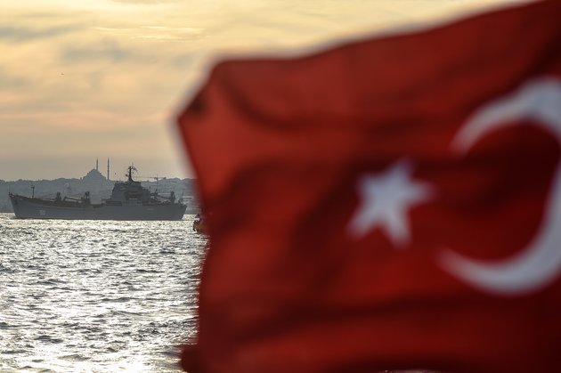 A Turkish flag flies on a ferry as Russian warship the BSF Saratov 150 sails through the Bosphorus off Istanbul en route to the eastern Mediterranean sea on September 26, 2015. AFP PHOTO/OZAN KOSE        (Photo credit should read OZAN KOSE/AFP/Getty Images)