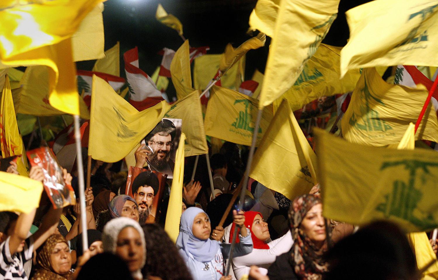 Images of Hezbollah chief Hassan Nasrallah are seen among scores of Hezbollah and Lebanese national flags being waved by Hezbollah supporters during a ceremony to mark first anniversary of the war with Israel, 14 August 2007. Nasrallah reiterated to a mass rally broadcast live on television that his Shiite group had won a divine victory. "Today is the anniversary of the divine victory," Nasrallah told the thousands of men, women and children who had gathered in an empty lot of Beirut's southern suburb of Dahiyeh controlled by Hezbollah. AFP PHOTO/MARWAN NAAMANI (Photo credit should read MARWAN NAAMANI/AFP/Getty Images)