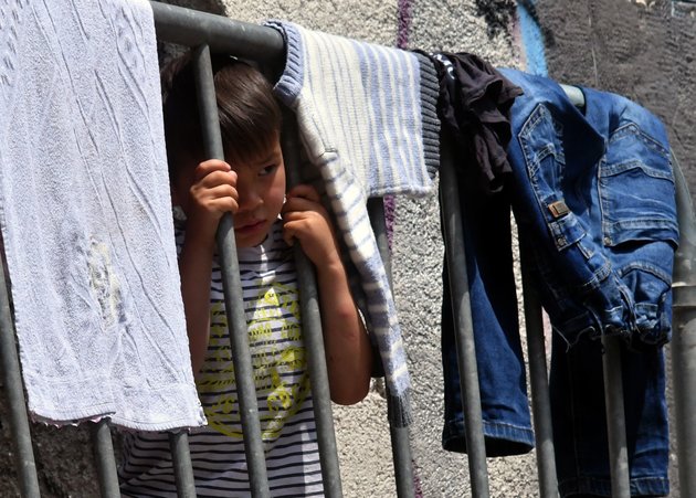 A child peeks through an improvised balcony fence, at the makeshift migrant center, in North-Western Bosnian town of Bihac, on May 31, 2018. - Bosnia, one of Europe's poorest countries, is so ill-equipped to cope with a surging influx of refugees that aid workers here fear the tiny nation could be on the brink of a humanitarian crisis. (Photo by ELVIS BARUKCIC / AFP)        (Photo credit should read ELVIS BARUKCIC/AFP/Getty Images)