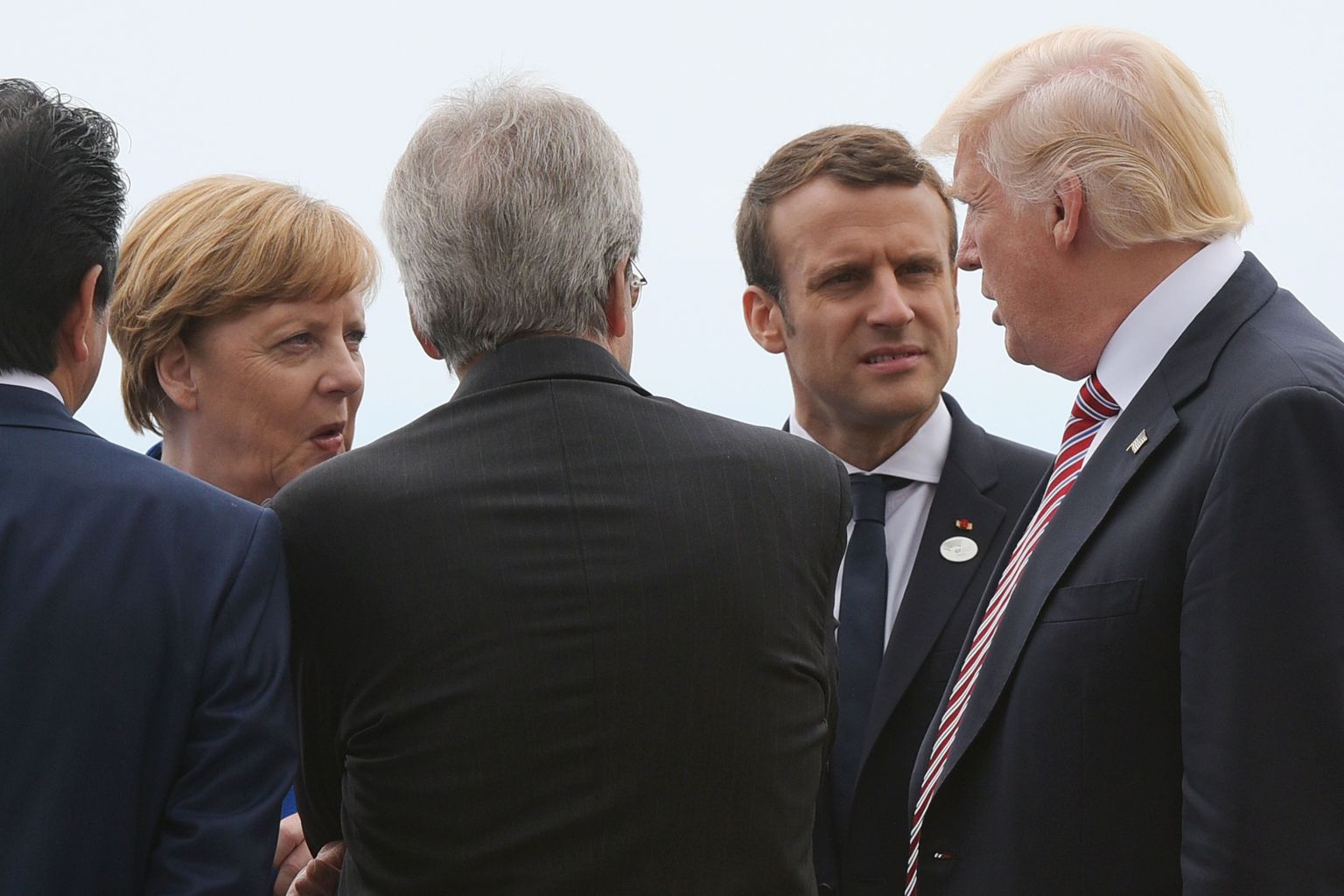 TOPSHOT - German Chancellor Angela Merkel (L) and French President Emmanuel Macron (2ndR) listen to US President Donald Trump at the Belvedere of Taormina during the Summit of the Heads of State and of Government of the G7, the group of most industrialized economies, plus the European Union, on May 26, 2017 in Sicily. The leaders of Britain, Canada, France, Germany, Japan, the US and Italy will be joined by representatives of the European Union and the International Monetary Fund (IMF) as well as teams from Ethiopia, Kenya, Niger, Nigeria and Tunisia during the summit from May 26 to 27, 2017. / AFP PHOTO / MANDEL NGAN (Photo credit should read MANDEL NGAN/AFP/Getty Images)